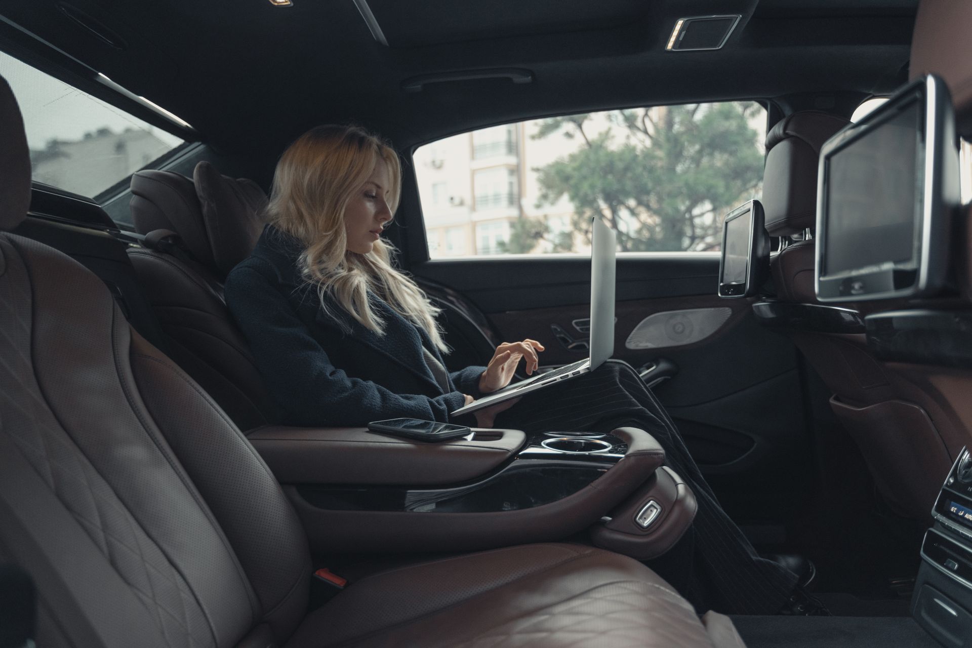 A principal working in the back of a chauffeured executive vehicle